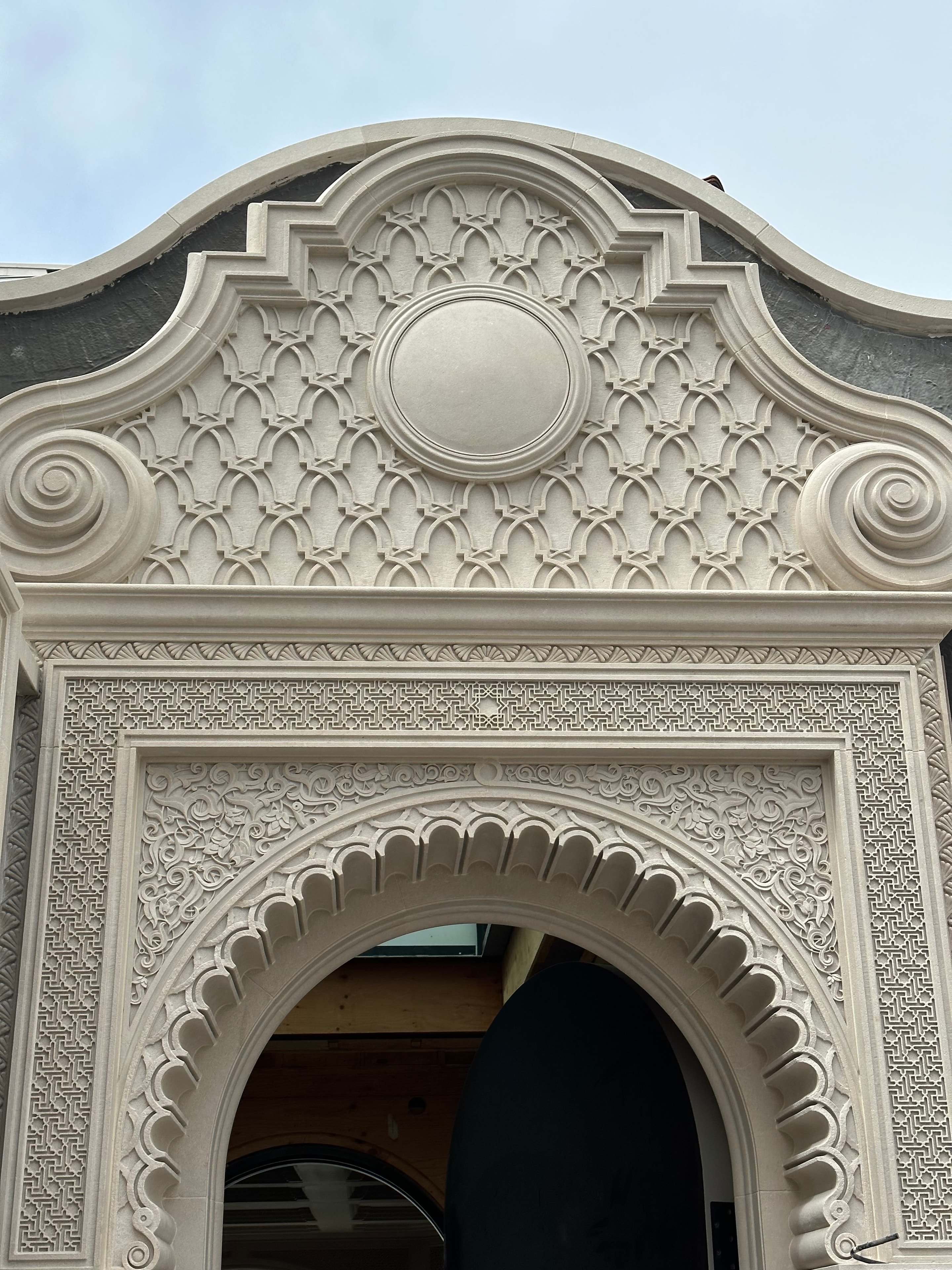 Decorative stone cornice with off-white cement surround and circular window detail