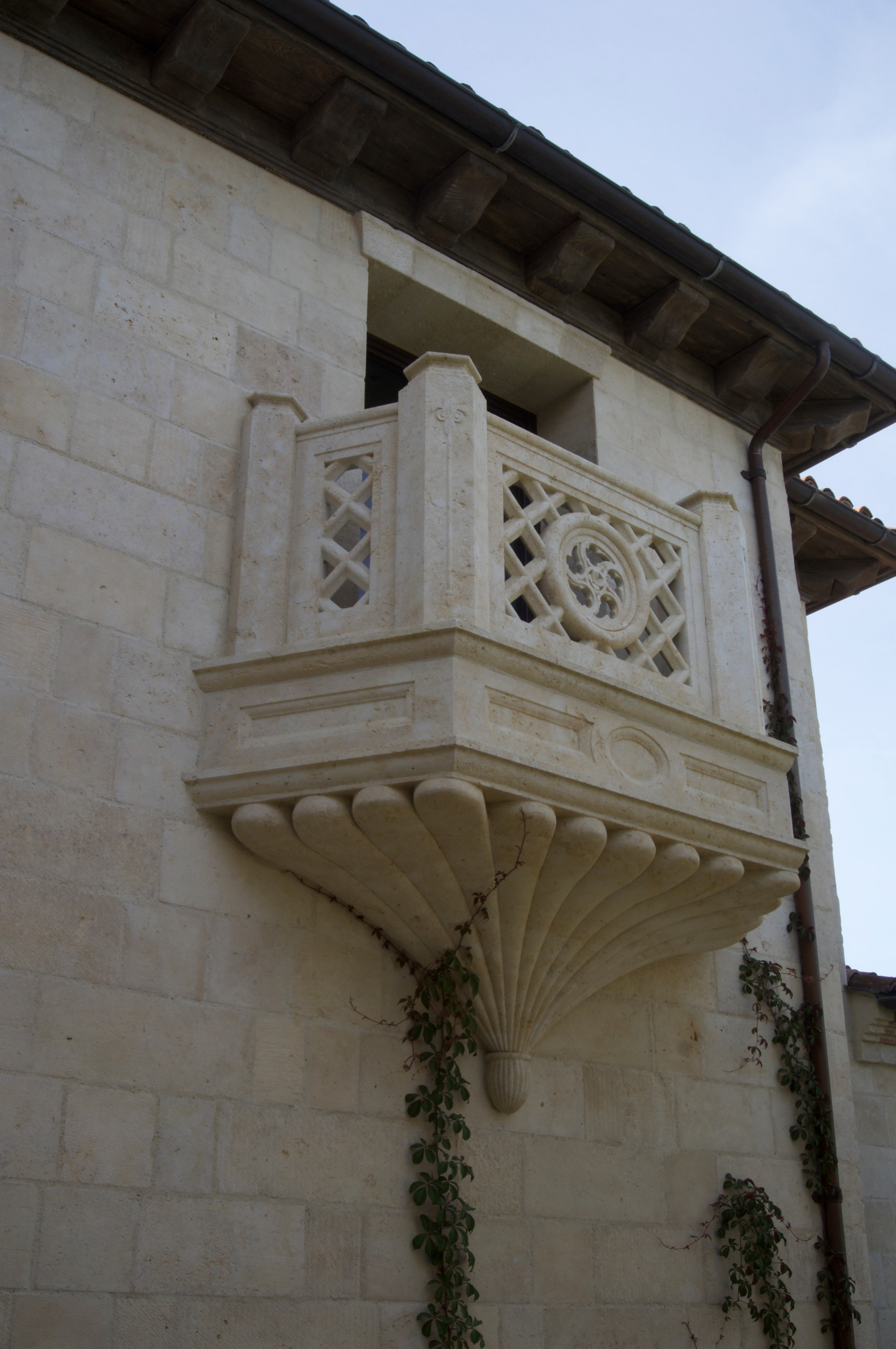 Ornate carved stone balcony with lattice railing and shell corbel