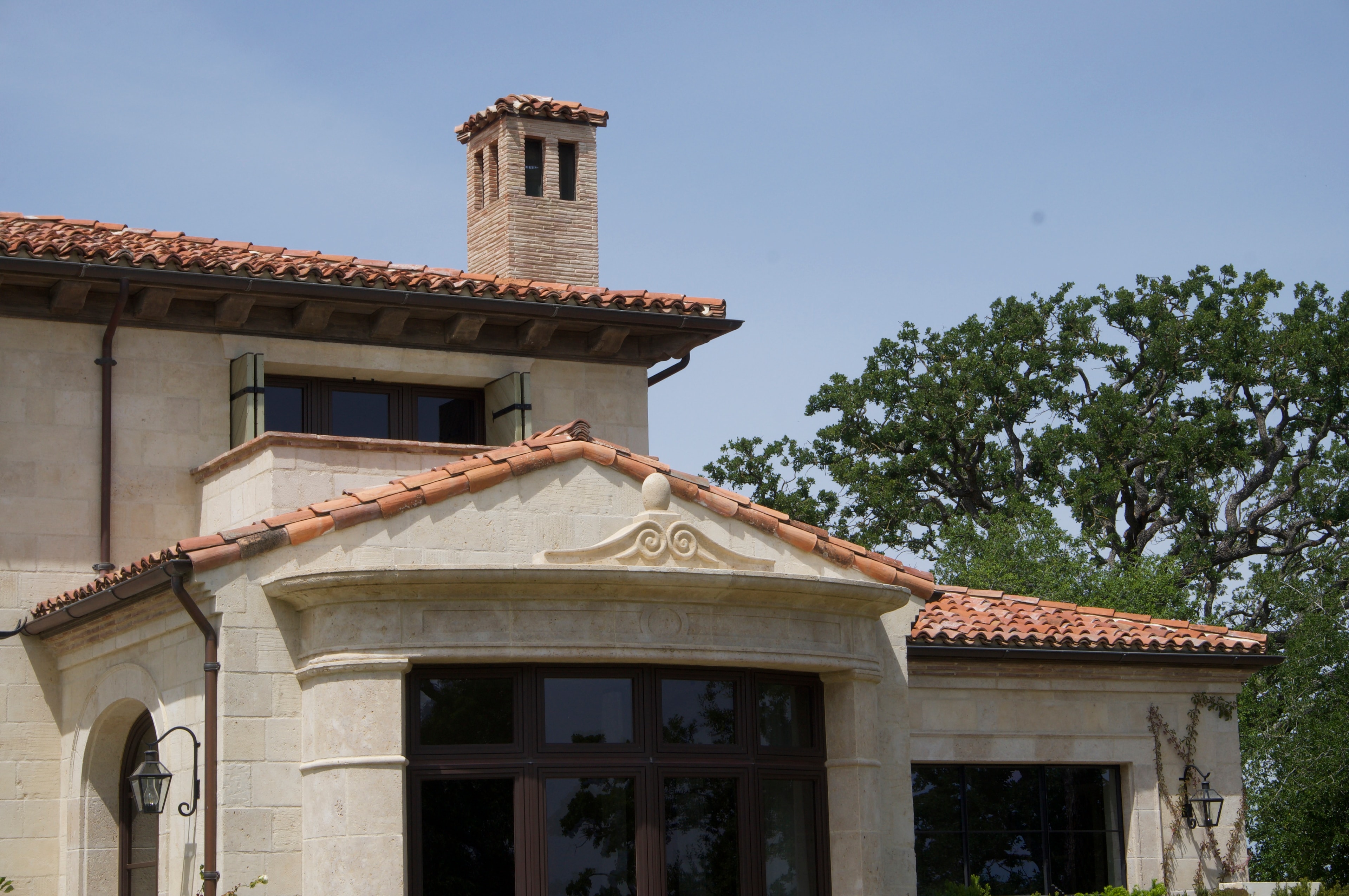 Stone facade with arched entry and olive trees