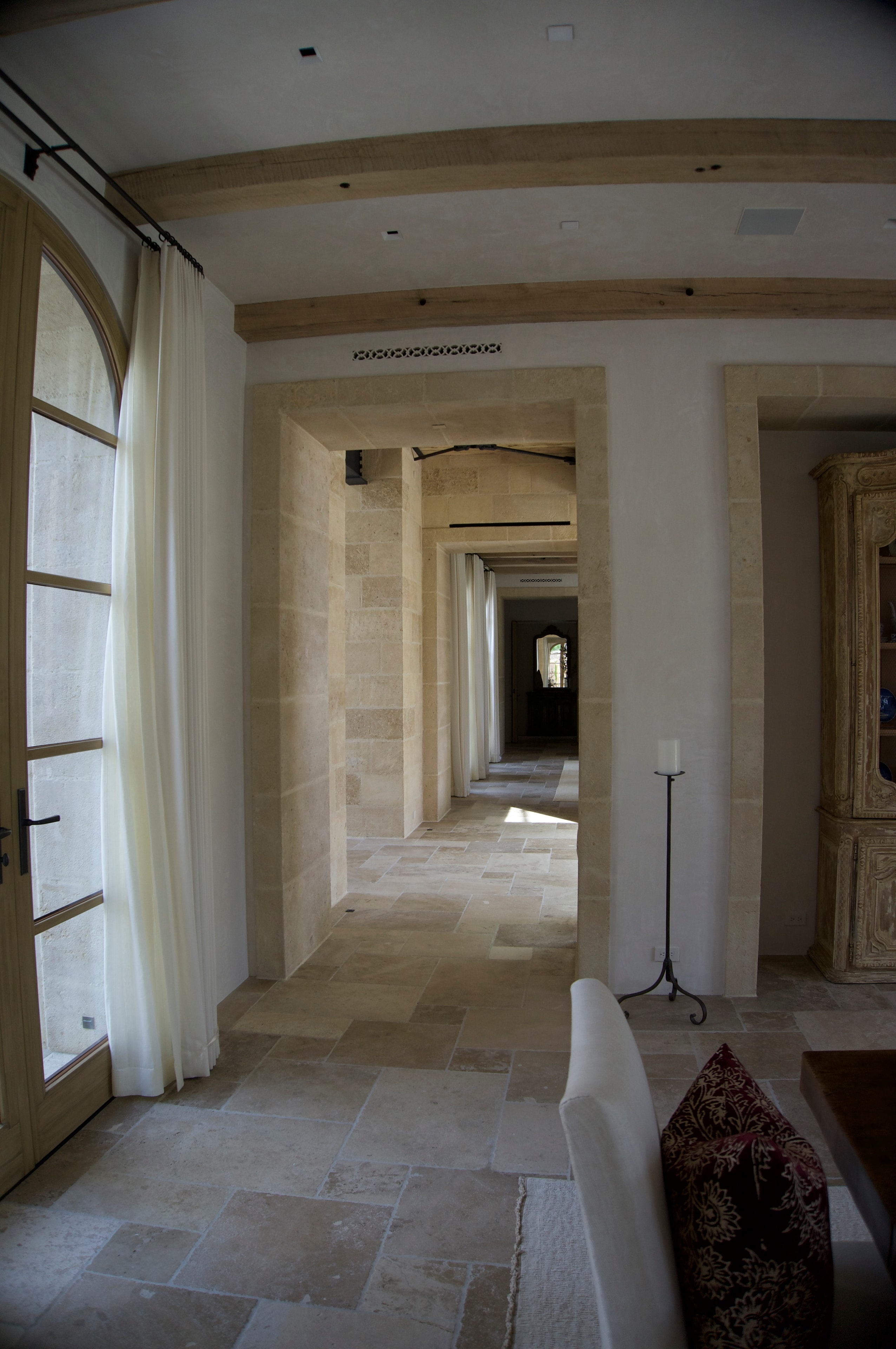 Stone-clad interior hallway with arched doorways and limestone floors